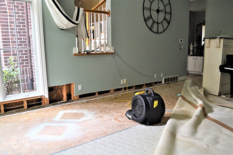 room that has been affected by storm damage, fan pointing toward wall to dry it